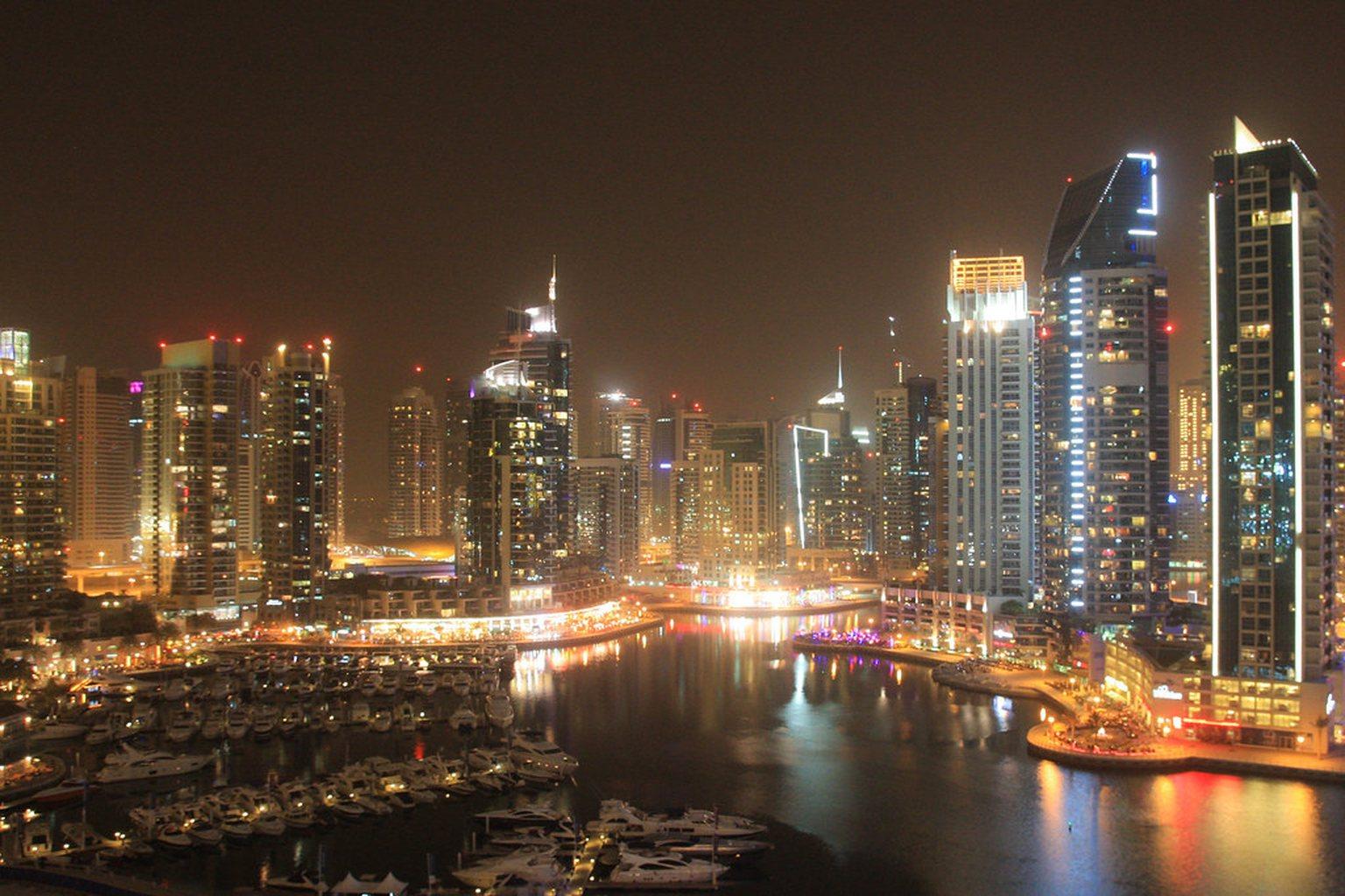The Marina outlook after dark from high in the tower: the yacht harbour directly below, the promenade lit gold along both banks and the tower wall rising on the far side of the water.